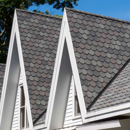 Grey luxury asphalt shingles with a scalloped shake profile on the steep gables of a home