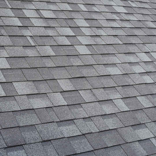 Close up of grey architectural asphalt shingles in good condition on a sloped roof
