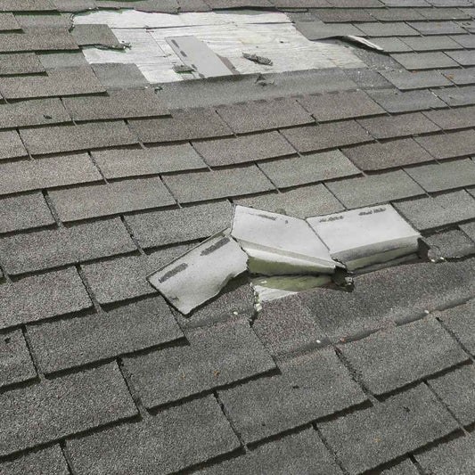 Wind damaged asphalt shingle roof with shingles torn away and the decking exposed in western North Carolina
