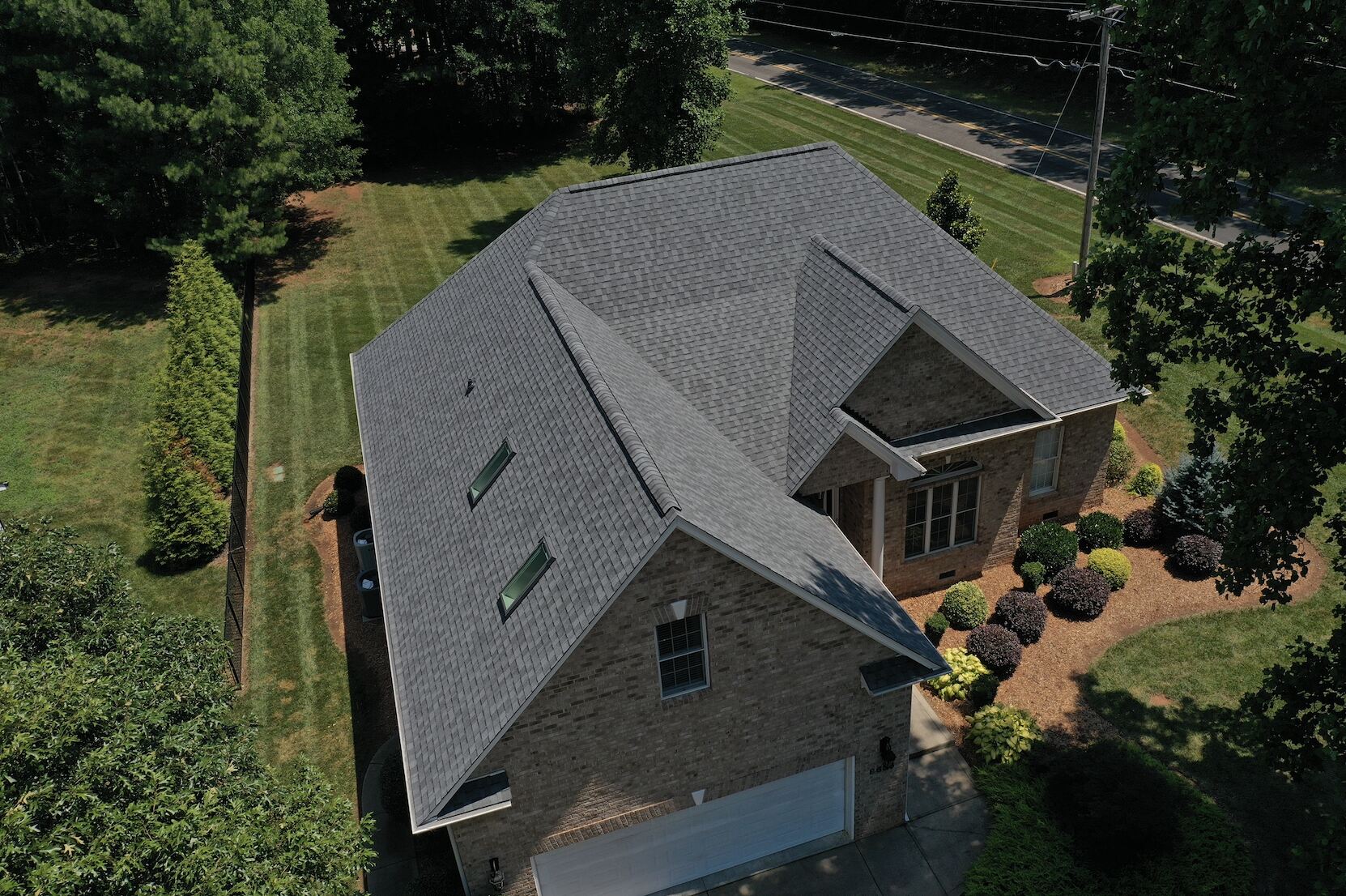 Aerial view of a house with a new roof and brick facade, surrounded by greenery near Lake Norman, NC