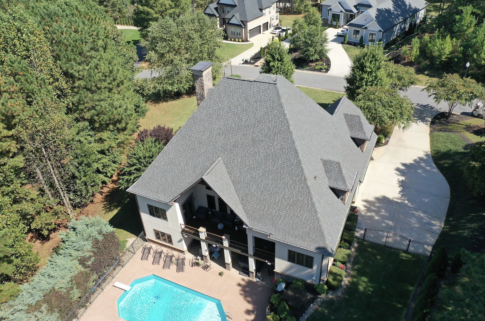 Aerial view of a large house with a pool and a new roof surrounded by trees in Hickory NC